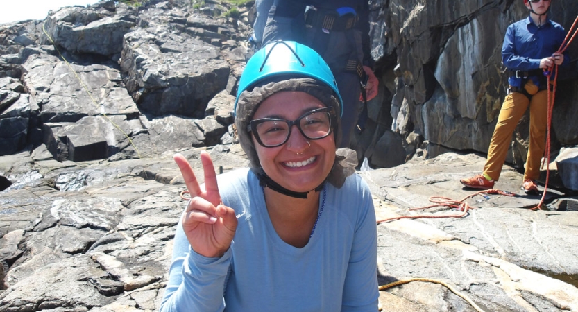 A person wearing a helmet gives the camera a peace sign. 